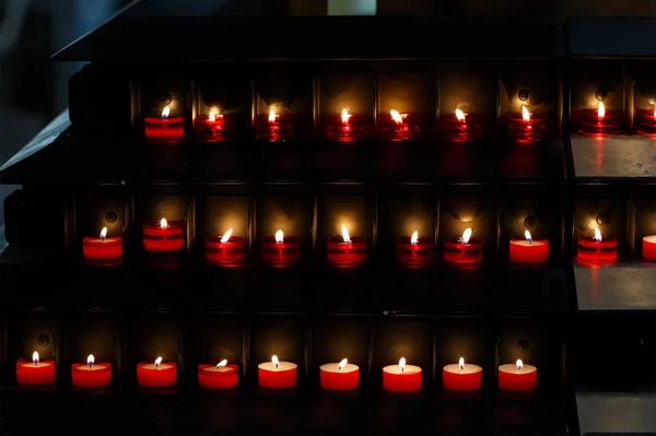 Gran grupo de velas encendidas en un fondo negro en el chur —  Fotos de Stock