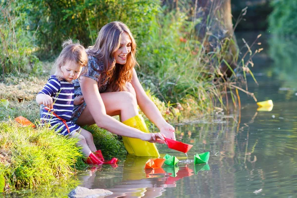 Adorable petite fille et sa mère jouer avec des bateaux en papier dans un r — Photo