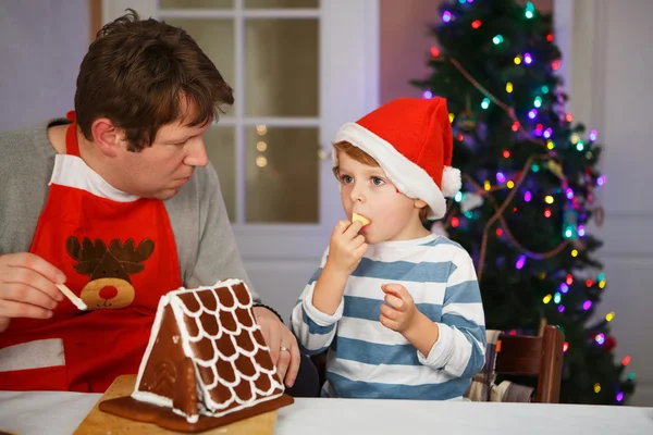 Vater und kleiner Sohn beim Zubereiten eines Lebkuchenhauses — Stockfoto