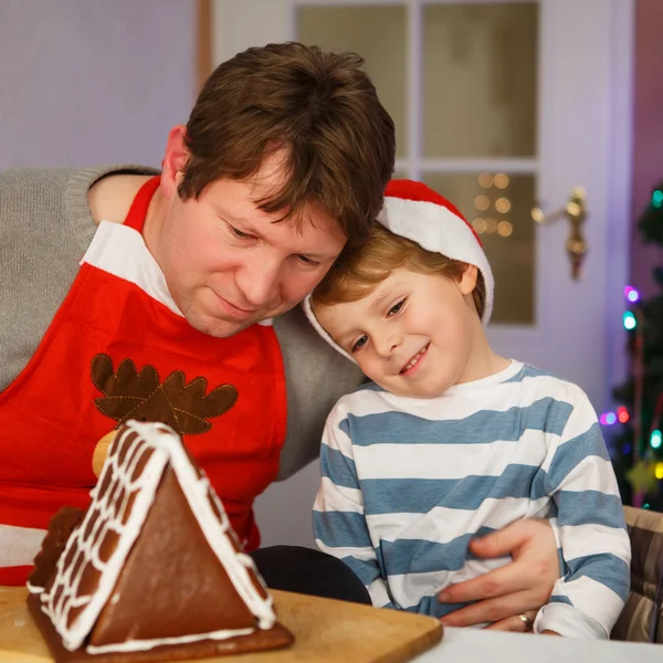 Vater und kleiner Sohn beim Zubereiten eines Lebkuchenhauses — Stockfoto