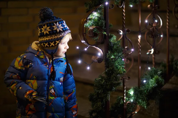 Kleiner Kleinkind-Junge steht zur Weihnachtszeit am Fenster und hält — Stockfoto