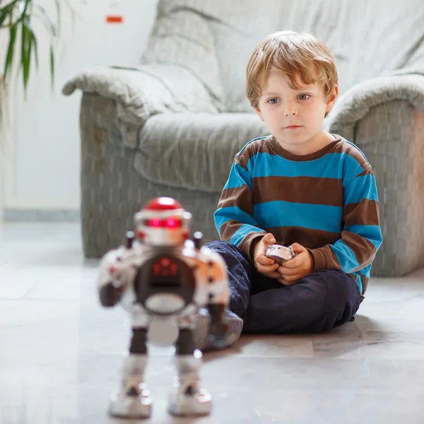 Evde, robot oyuncak ile kapalı oynayan küçük sarışın çocuk. — Stok fotoğraf