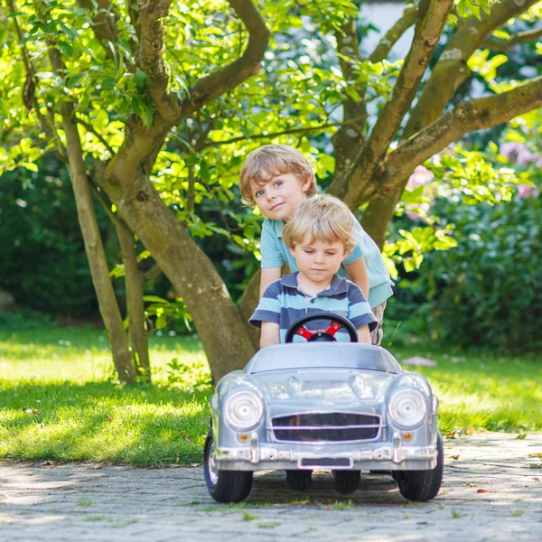 Zwei glückliche Zwillingsjungen spielen mit Spielzeugauto — Stockfoto