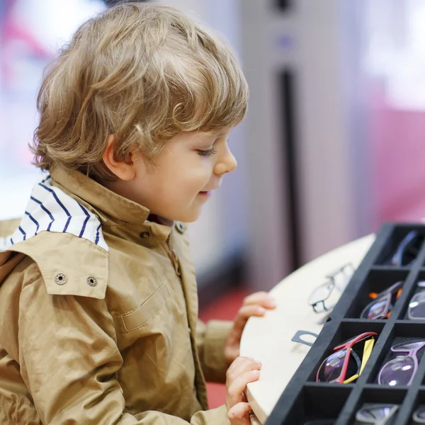 Carino bambino ragazzo a ottico negozio durante la scelta il suo nuovo gl — Foto Stock