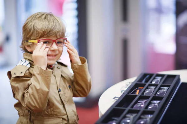 Lindo niño en la tienda de óptica durante la elección de su nuevo gl —  Fotos de Stock