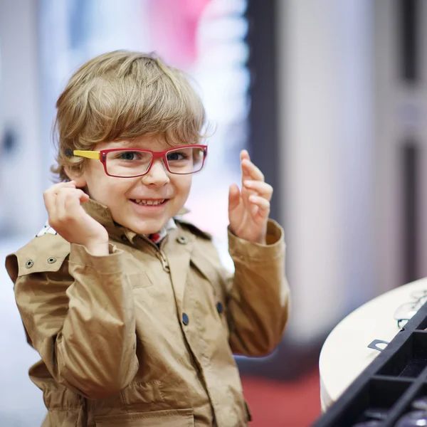 Lindo niño en la tienda de óptica durante la elección de su nuevo gl —  Fotos de Stock