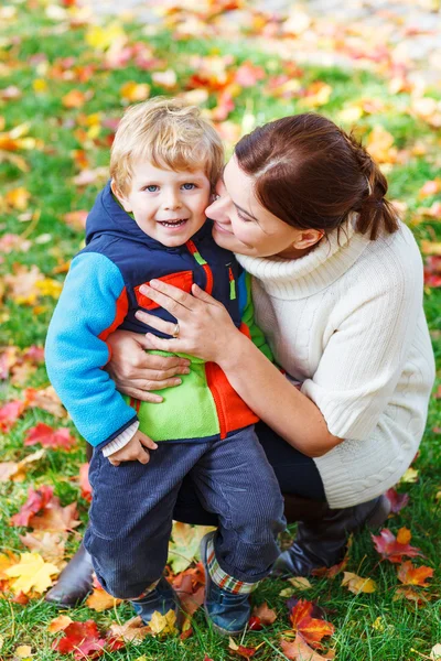Young mum and her little kid son hugging together in autumn park — Stock Photo, Image