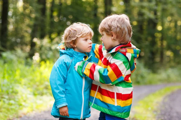 Dois meninos irmãos em capas coloridas e botas andando — Fotografia de Stock
