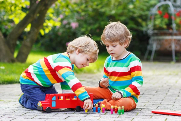 Δύο αδέλφια, παιδί αγόρια παίζουν με κόκκινο σχολικό λεωφορείο — Φωτογραφία Αρχείου