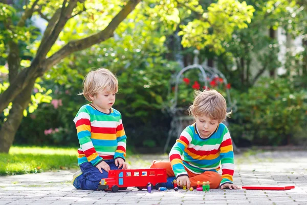 Dwóch przyjaciół chłopca, grając z czerwony autobus szkolny — Zdjęcie stockowe