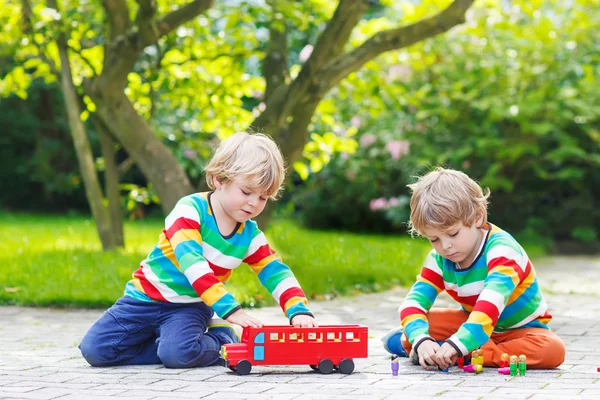 Dos chicos gemelos jugando con el autobús escolar rojo —  Fotos de Stock