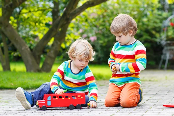 Dois amiguinhos brincando com ônibus escolar vermelho — Fotografia de Stock