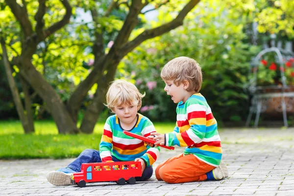 Dos niños pequeños jugando con el autobús escolar rojo —  Fotos de Stock