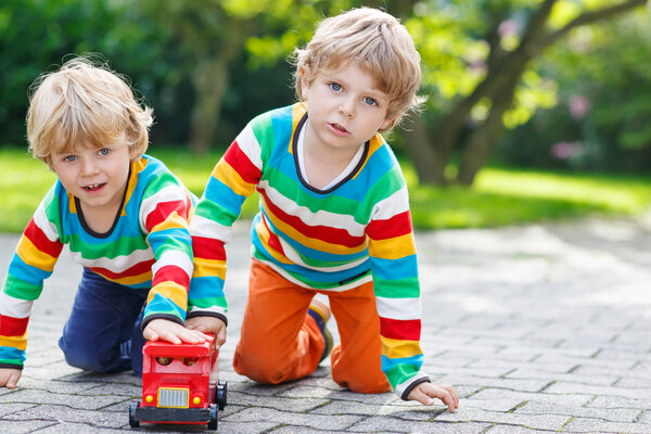 Two siblings, kid boys playing with red school bus