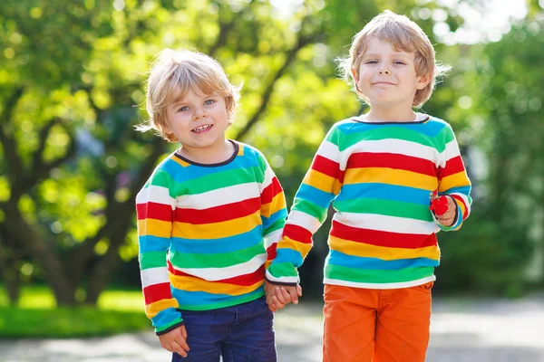 Dois irmãos mais novos crianças em roupas coloridas andando mão i — Fotografia de Stock