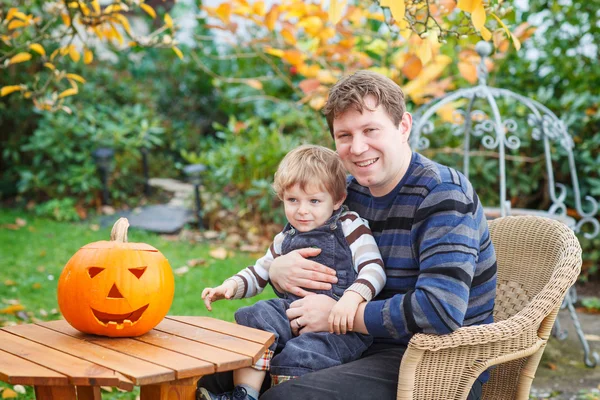 Jonge man en peuter jongen halloween pompoen maken — Stockfoto