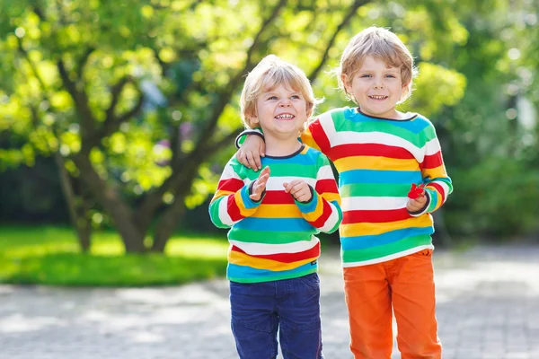 Two little kid boys in colorful clothing walking hand in hand — Stock Photo, Image