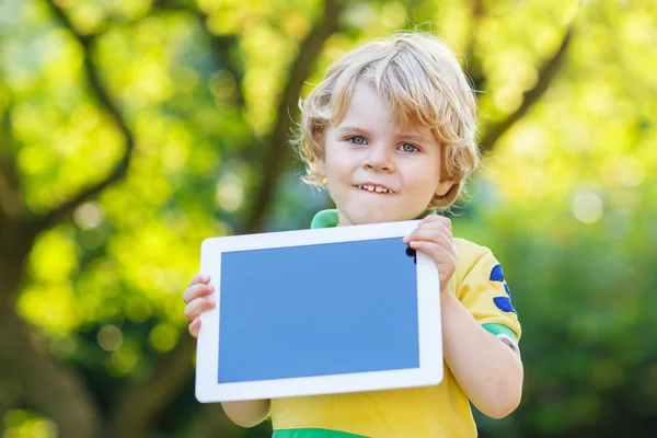 Bedårande glad liten unge pojke håller TabletPC, utomhus — Stockfoto
