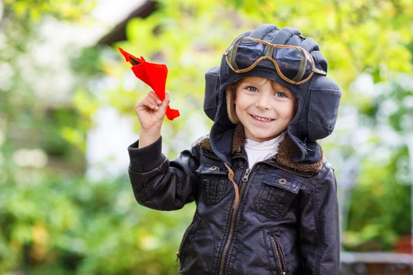 Enfant heureux dans un casque de pilote jouant avec un avion jouet — Photo