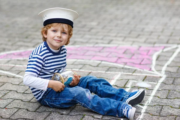 Little boy having fun with ship picture drawing with chalk — Stock Photo, Image