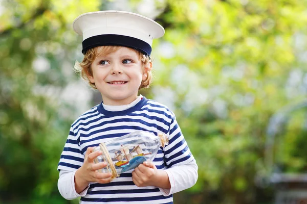 Enfant heureux en uniforme de skipper jouant avec le bateau jouet — Photo