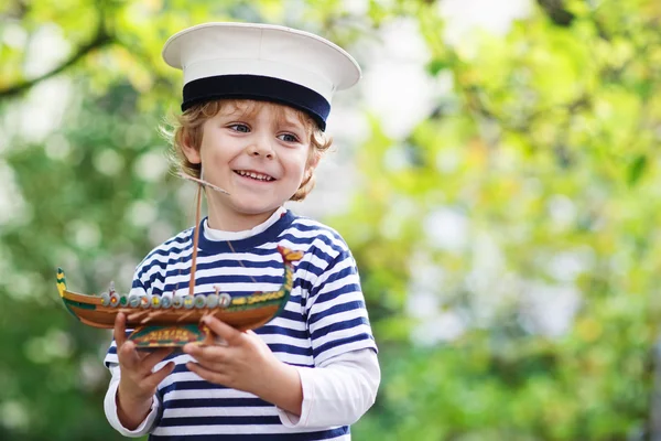 Szczęśliwe dziecko w jednolite, bawiąc się zabawkami statek kapitana — Zdjęcie stockowe