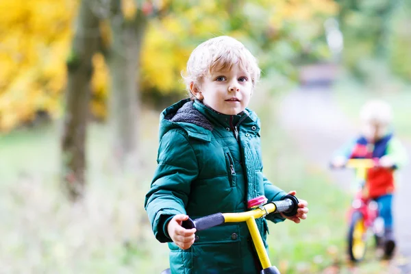 Två små syskon pojkar har roligt på cyklar i höst skog. — Stockfoto