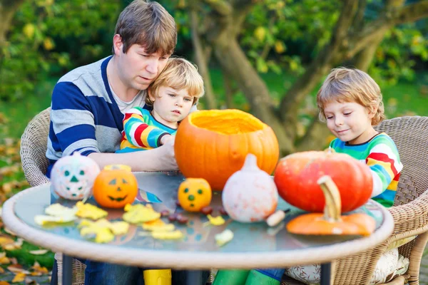 Young dad and two little sons making jack-o-lantern for hallowee — Stock Photo, Image