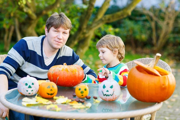 Young dad and his little son making jack-o-lantern for halloween — Stock Photo, Image