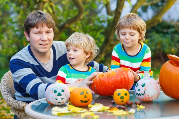 Joven padre y dos hijos pequeños haciendo jack-o-linterna para hallo — Foto de Stock