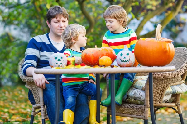 Dad and two little sons making jack-o-lantern for halloween in a — Stock Photo, Image