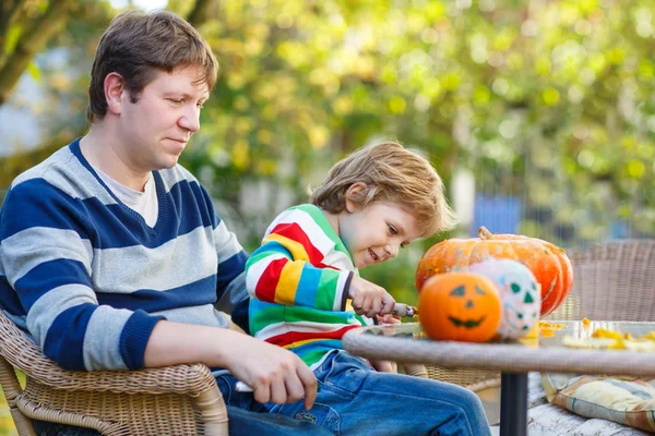 Mladý otec a jeho malý syn dělat jack-o lucernou pro halloween — Stock fotografie