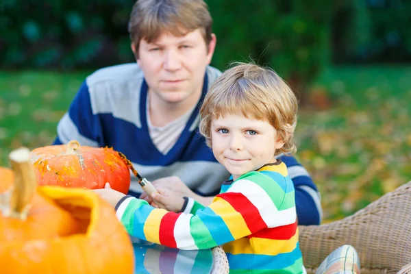 Young dad and his little son making jack-o-lantern for halloween Stock Picture
