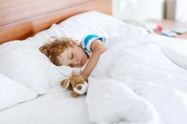 Uyku ve oyuncak ile onun beyaz yatakta hayal sevimli çocuk çocuk