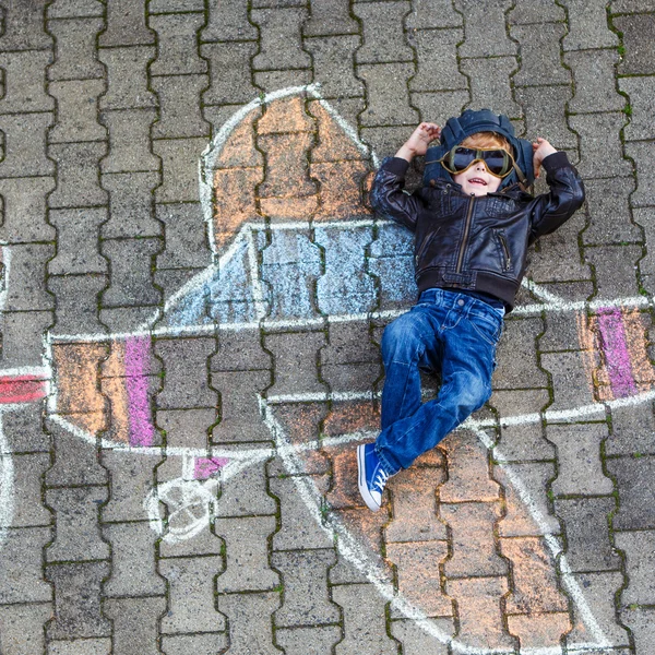 Menino se divertindo com desenho de imagem de avião com giz — Fotografia de Stock