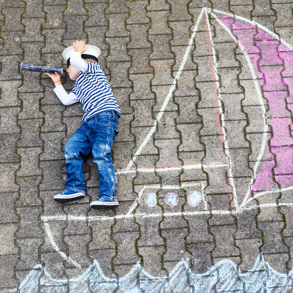 Little boy having fun with ship picture drawing with chalk — Stock Photo, Image