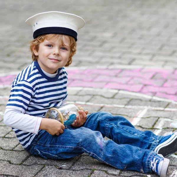 Little boy having fun with ship picture drawing with chalk — Stock Photo, Image