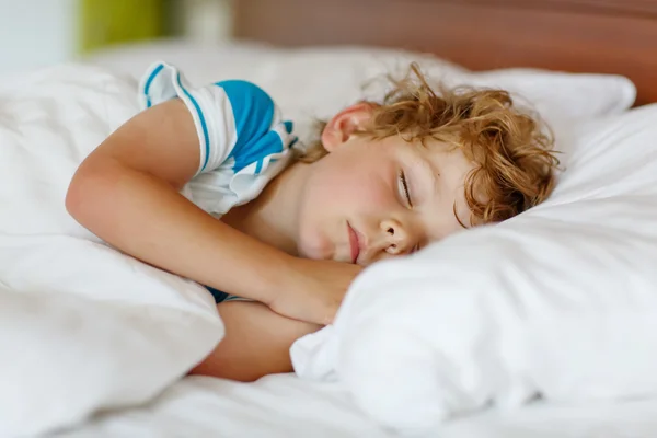 Pequeño chico rubio durmiendo en su cama . — Foto de Stock