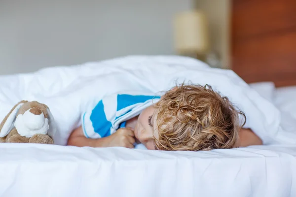 Adorable niño durmiendo y soñando en su cama blanca con juguete — Foto de Stock