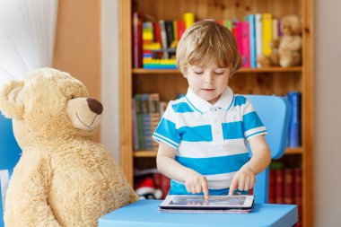 Onun odasında evde tablet bilgisayar ile oynayan sevimli çocuk