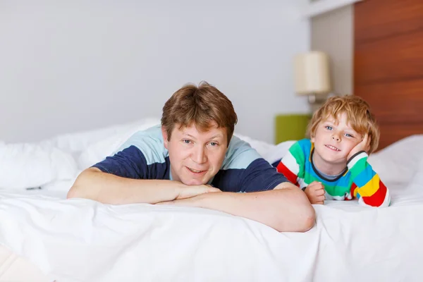 Father and his little kid son relaxing and resting in white bed — Stock Photo, Image