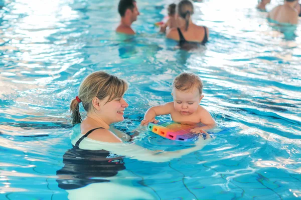 Pequeño niño y su madre aprendiendo a nadar en un swi interior — Foto de Stock