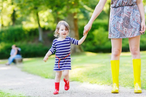 Mamma och lilla bedårande barn flicka i gummi stövlar att ha kul — Stockfoto