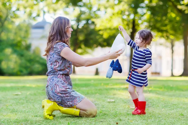 Mother and little adorable child in yellow and red rubber boots — Stock Photo, Image