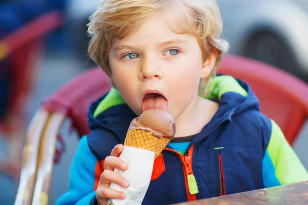 Malá blonďatá batole dítě jíst čokoládová zmrzlina — Stock fotografie