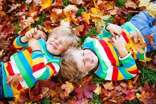 Két kis gyerek fiú Fektetése Őszi levelek, a színes ruhák — Stock Fotó
