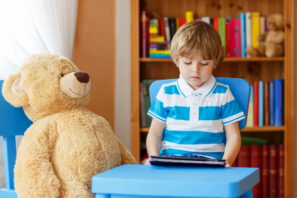 Детский сад мальчик играет с планшетным компьютером в своей комнате на хо — стоковое фото