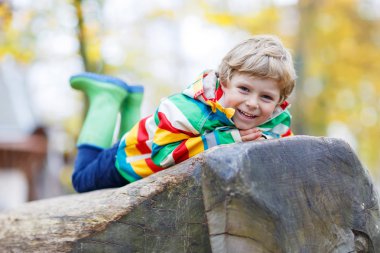 Adorable child boy having fun on autumn playground clipart