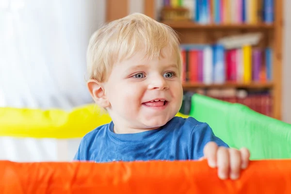 Cute little baby boy playing in colorful playpen, indoors — Stock Photo, Image