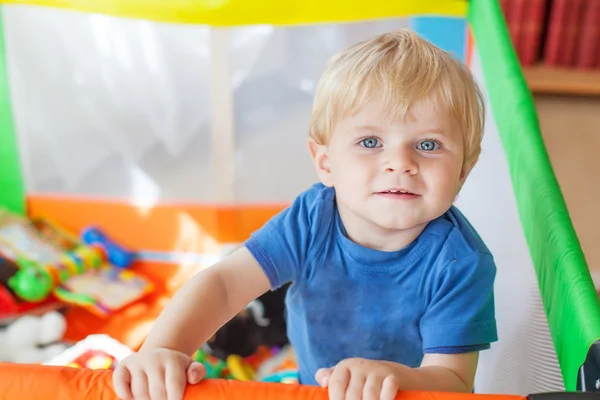 Schattige kleine babyjongen spelen in kleurrijke kinderbox, binnenshuis — Stockfoto